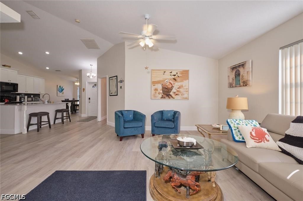 Open-plan living room with blue armchairs, a beige sofa, and an adjoining kitchen breakfast bar.