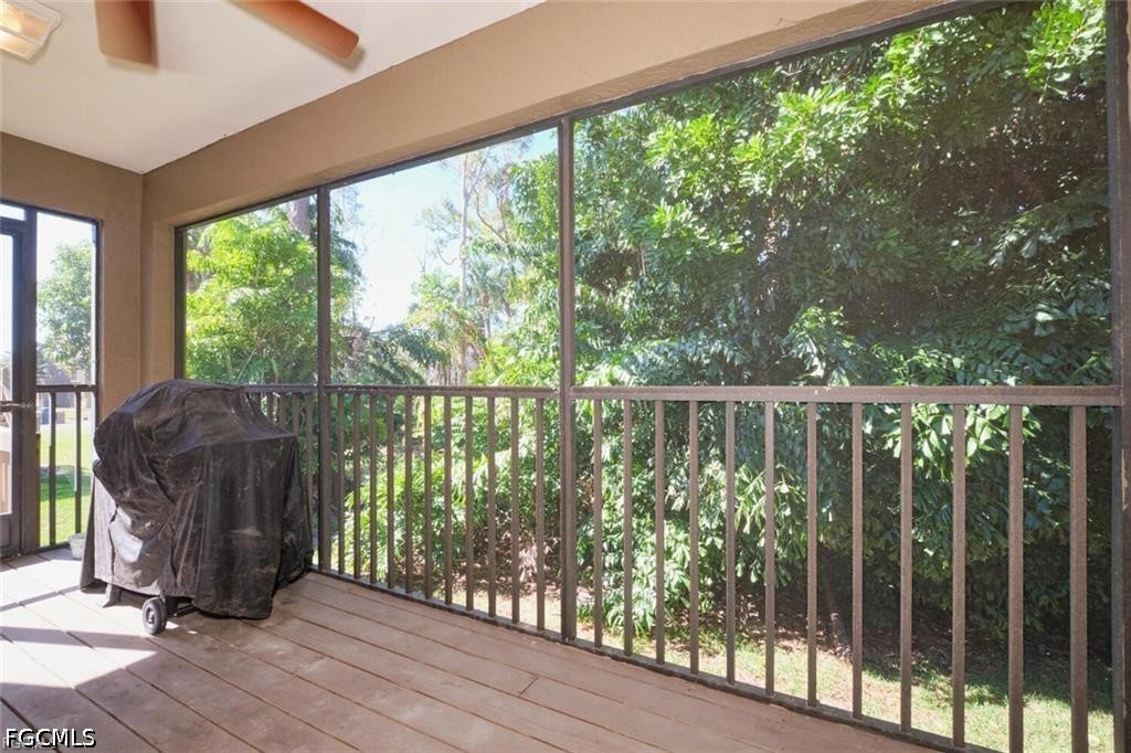 Screened lanai with tiled flooring, a covered grill, and a view of dense greenery.