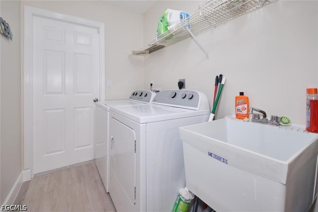 Laundry room with white washer and dryer, deep utility sink, and wire shelving.