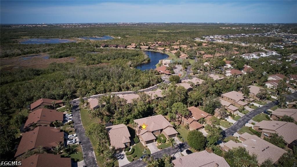 Aerial view of a home marked by a yellow star beside a wooded wetland and winding waterway.
