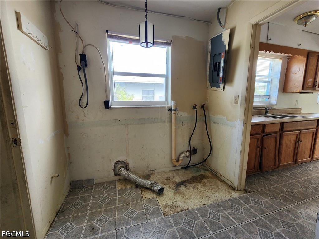 Laundry area with exposed washer hookups and a vent duct lying on the stained floor.