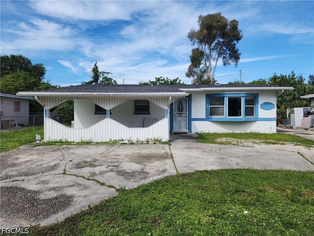Single-story home with blue trim, a covered carport, and a cracked concrete driveway.