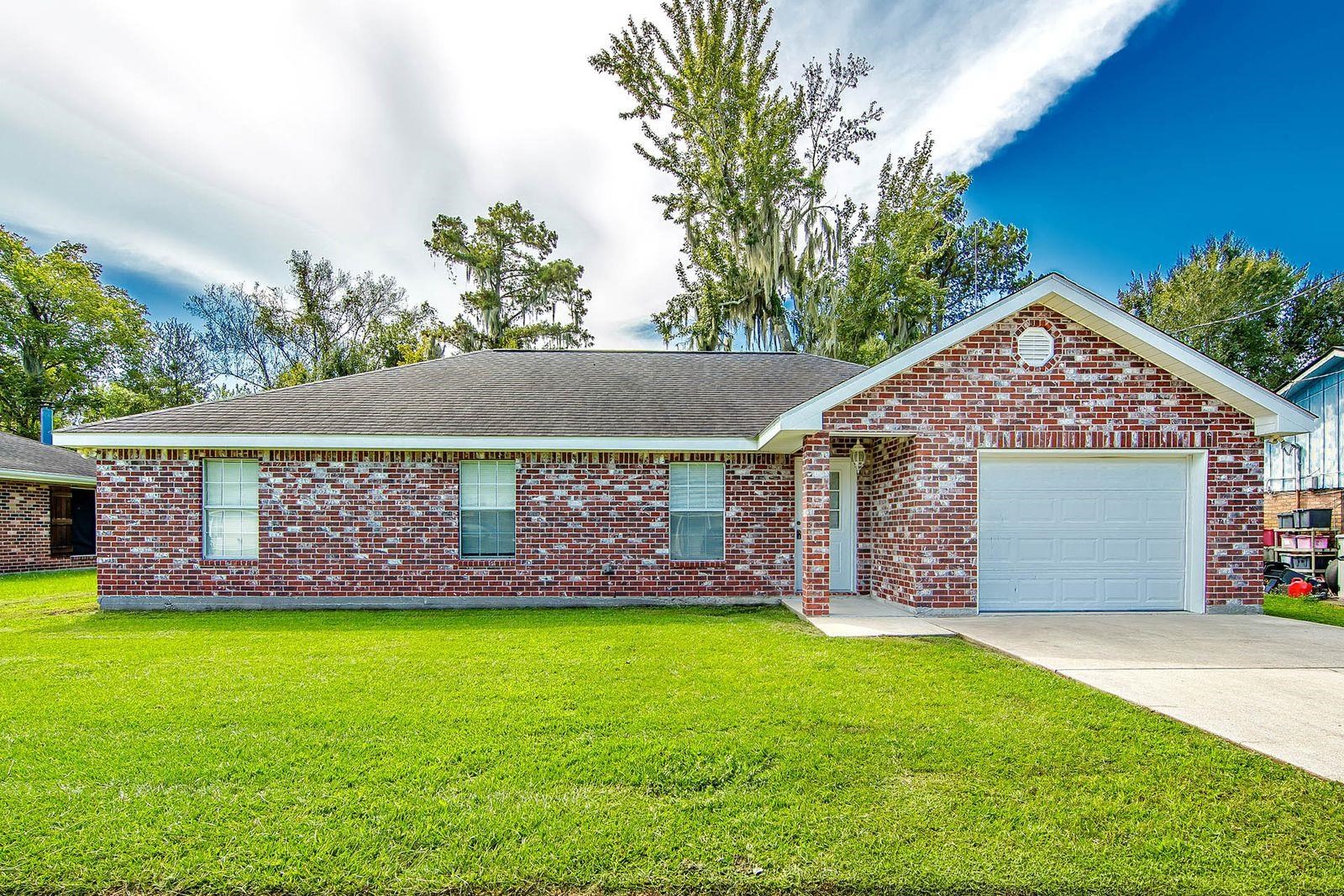 Single-story brick house with attached garage and a broad front lawn.