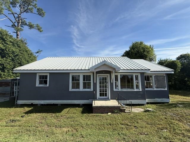 Single-story gray house with a light metal roof and central entrance.