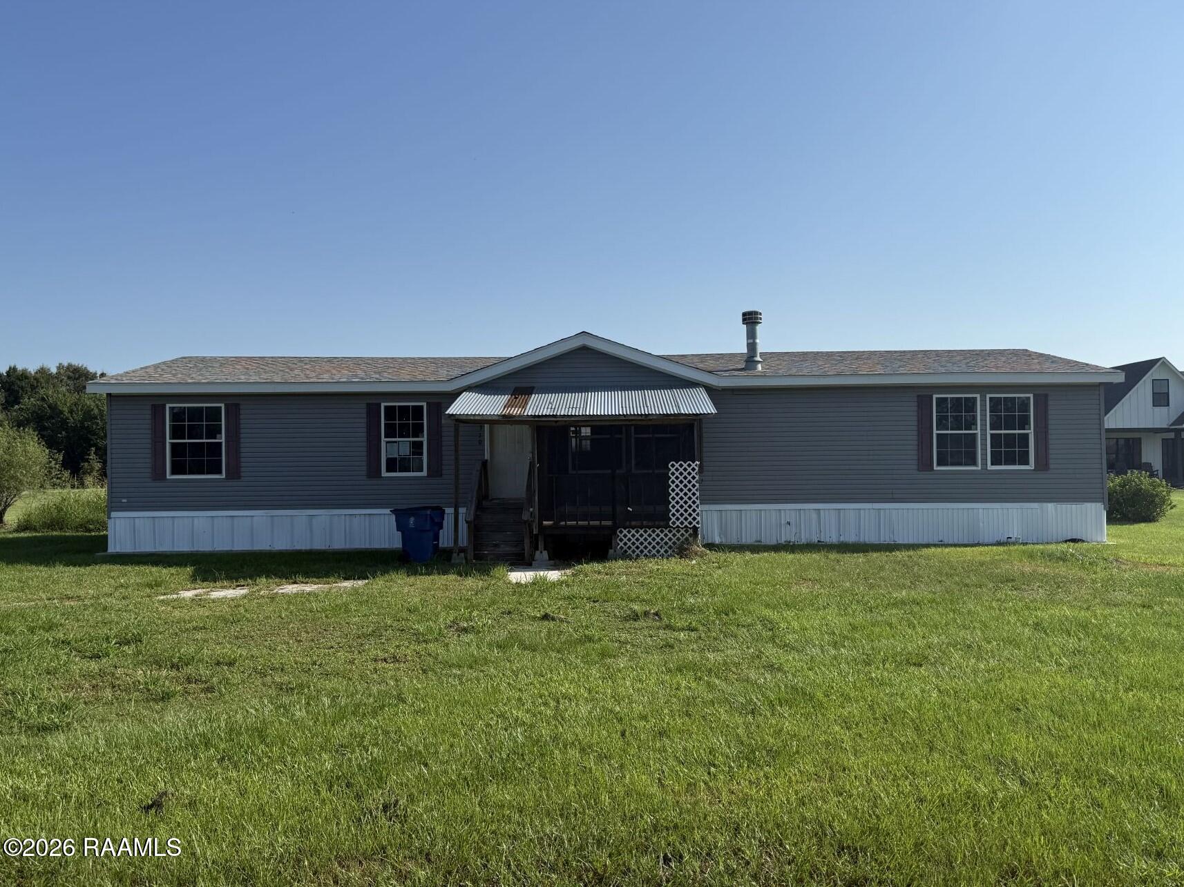 Gray single-story home with a covered porch and broad green lawn.