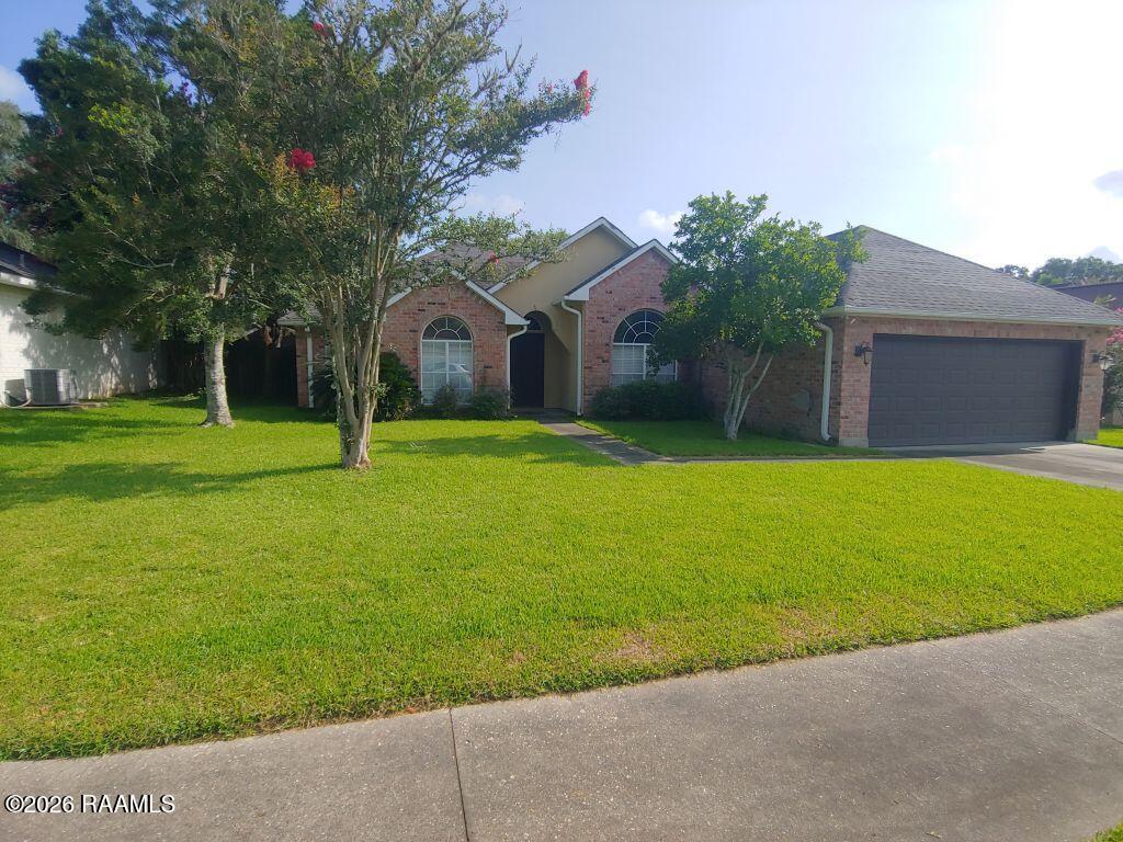 Brick house with an attached two-car garage, arched windows, and a broad lawn.