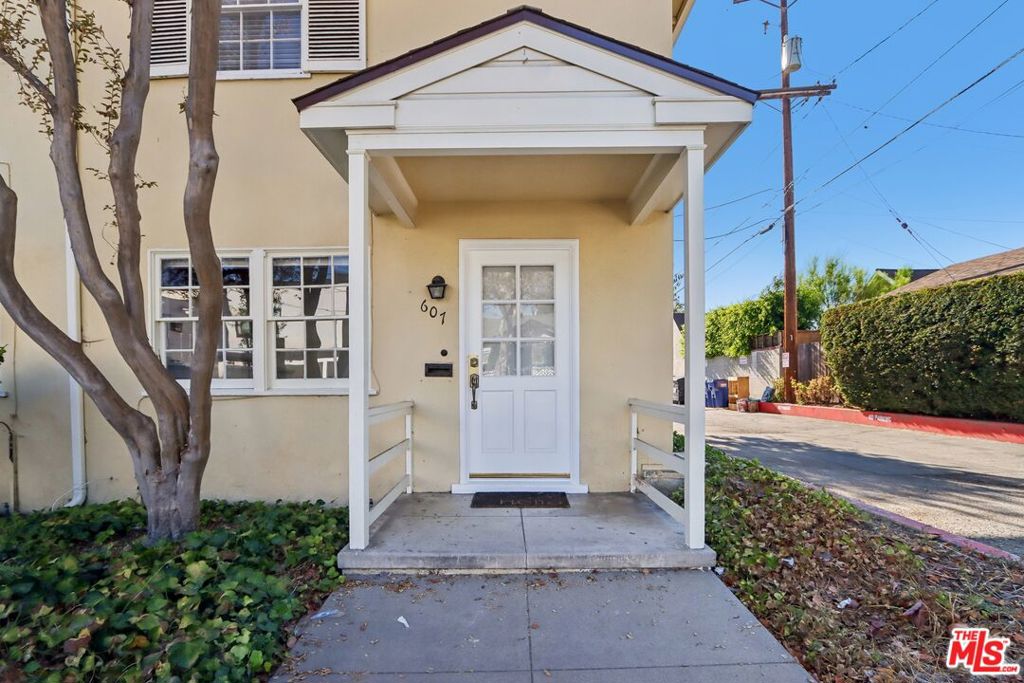 Pale yellow stucco home with a covered entry porch and white front door.
