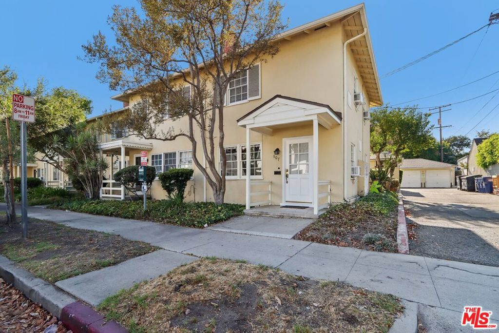 Cream two-story residence with a covered entry and driveway to a detached garage.