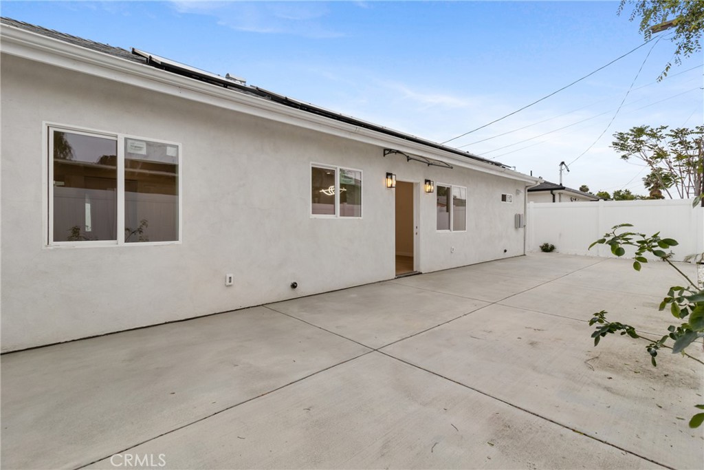 White stucco home with a wide concrete driveway, side windows, and an open entry door.