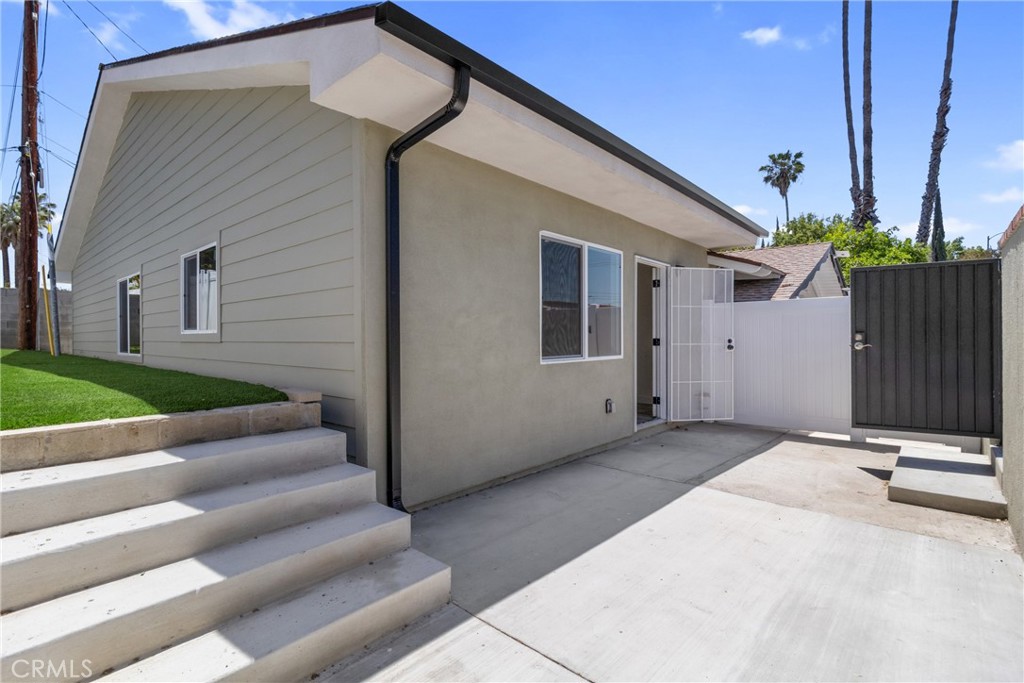 Single-story home with concrete steps and a gated driveway beside a small lawn.