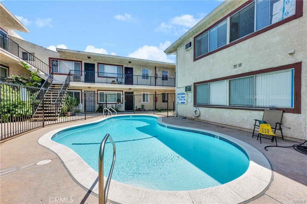 Courtyard pool at a two-story apartment building with exterior walkways and stairs.