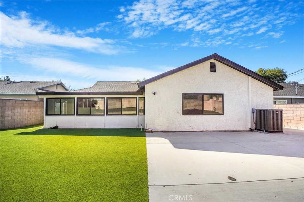 Rear of a single-story home with a broad concrete patio and green lawn.