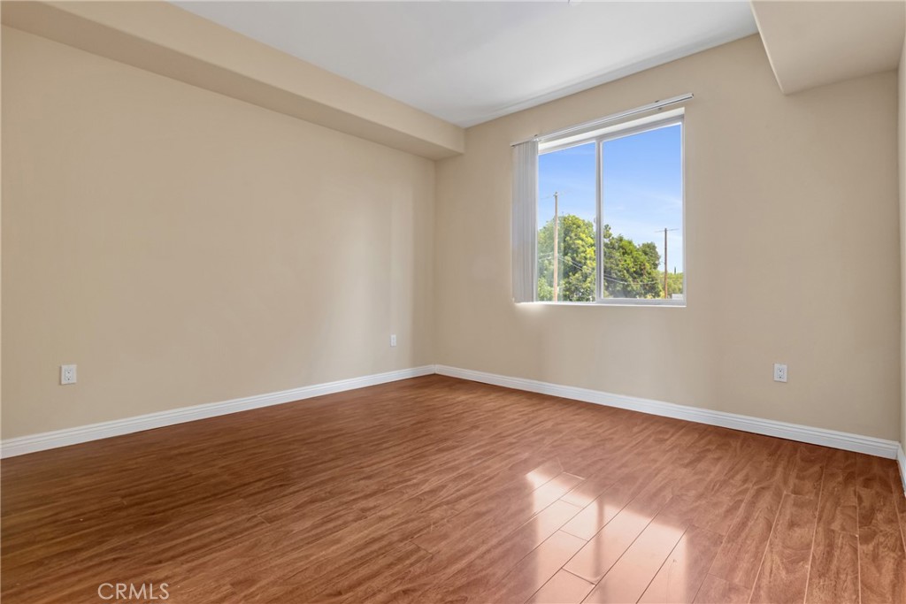 Empty room with wood-look flooring and a window overlooking trees.