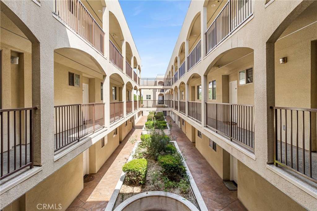 Apartment courtyard with arched walkways, metal balconies, and a landscaped garden.