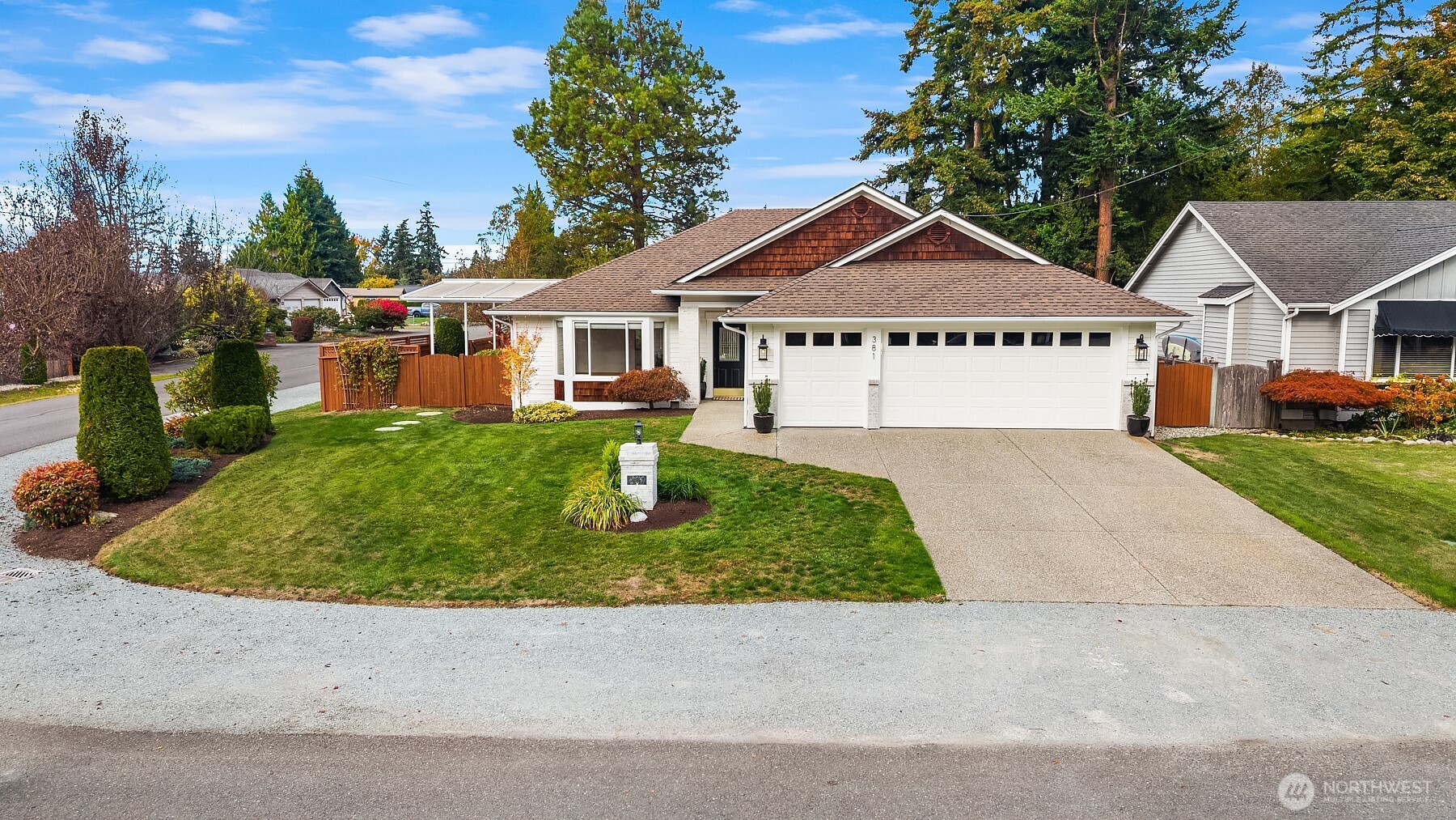 Street-facing home with a white double garage, brown shingle gables, and landscaped front lawn.