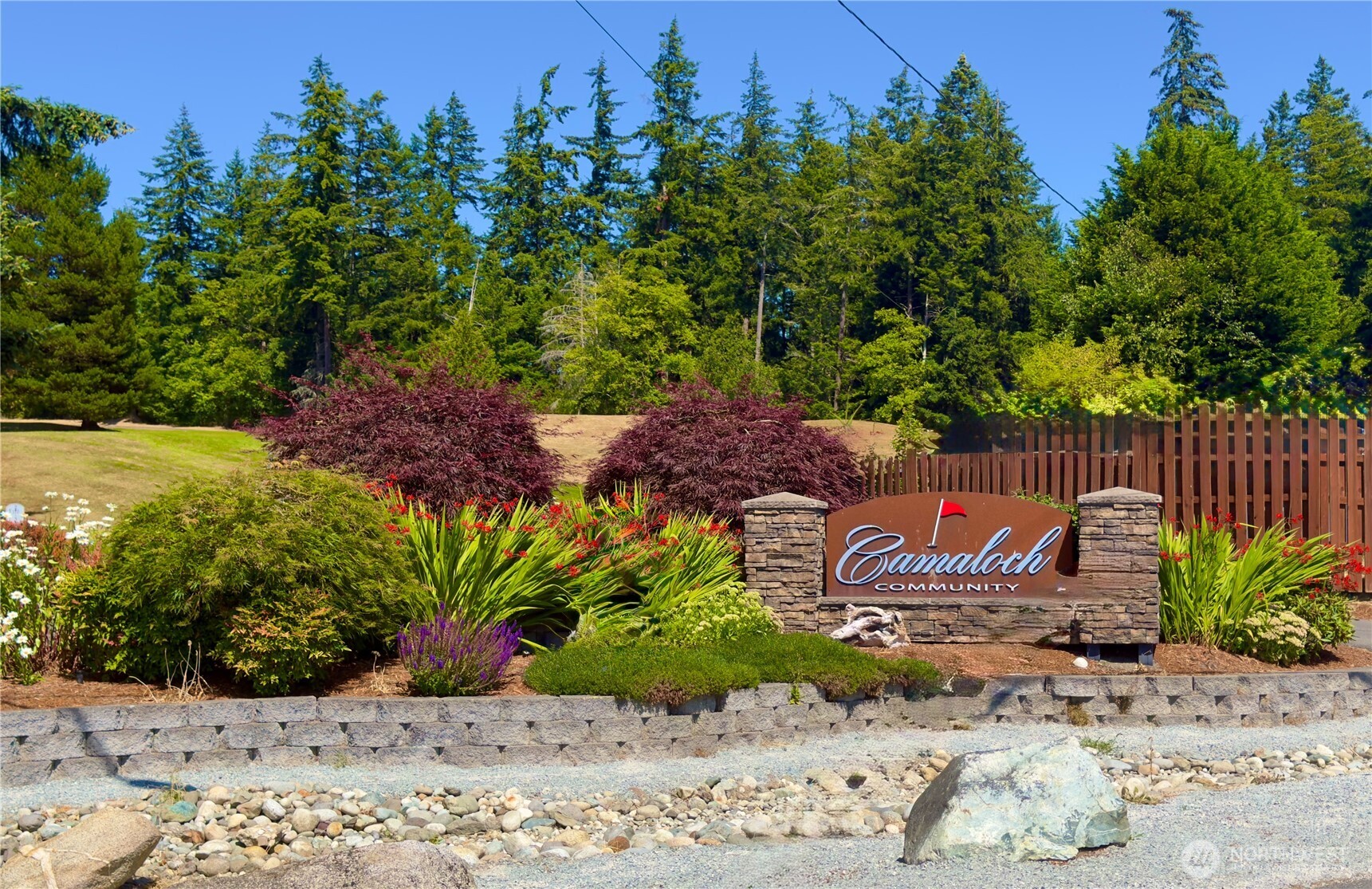 Camaloch community entrance sign amid landscaped gardens and evergreen trees.