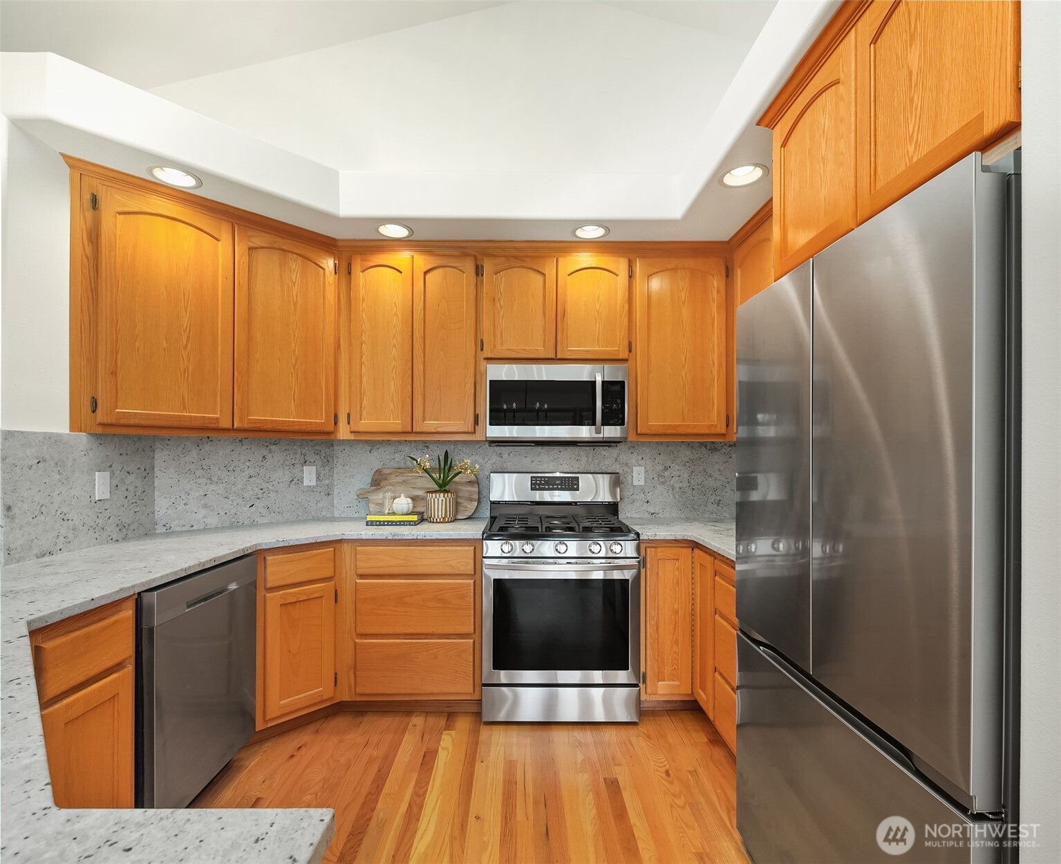 Kitchen with warm wood cabinets, gray stone counters, and stainless steel appliances.