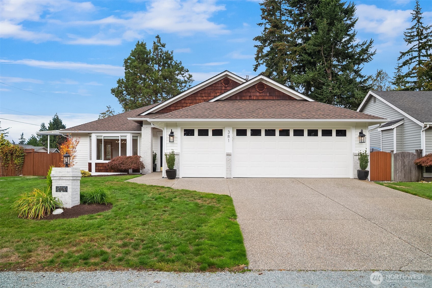 White house with a wide double garage, concrete driveway, and landscaped front lawn.