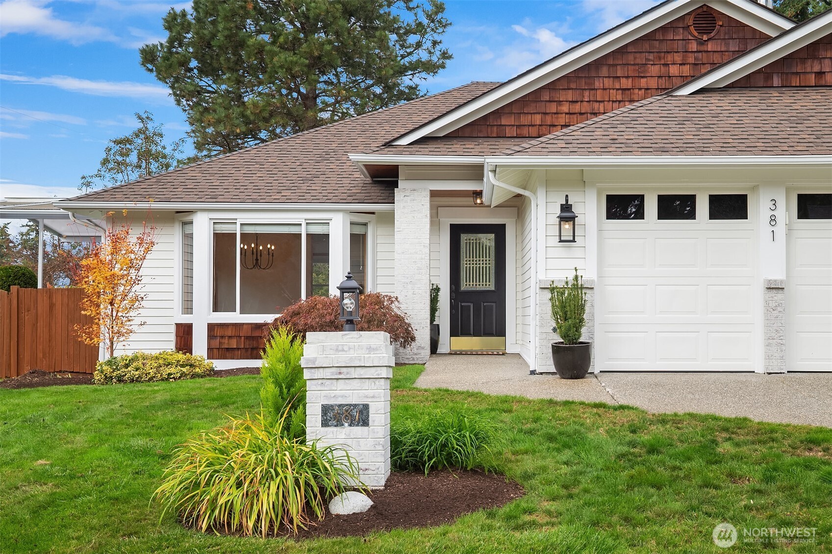 White house with cedar-shingle gable, garage, and landscaped front lawn.