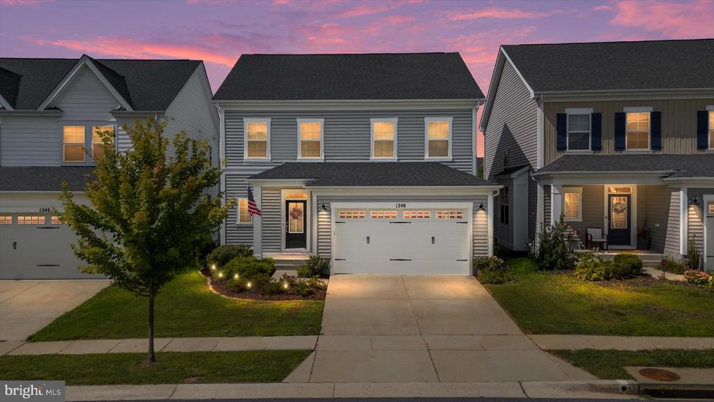 Gray two-story home with an attached garage and landscaped front yard at dusk.