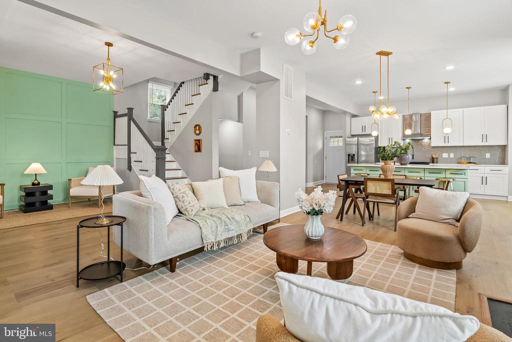Open-plan living room with mint-green accent wall, white sofa, and kitchen beyond.