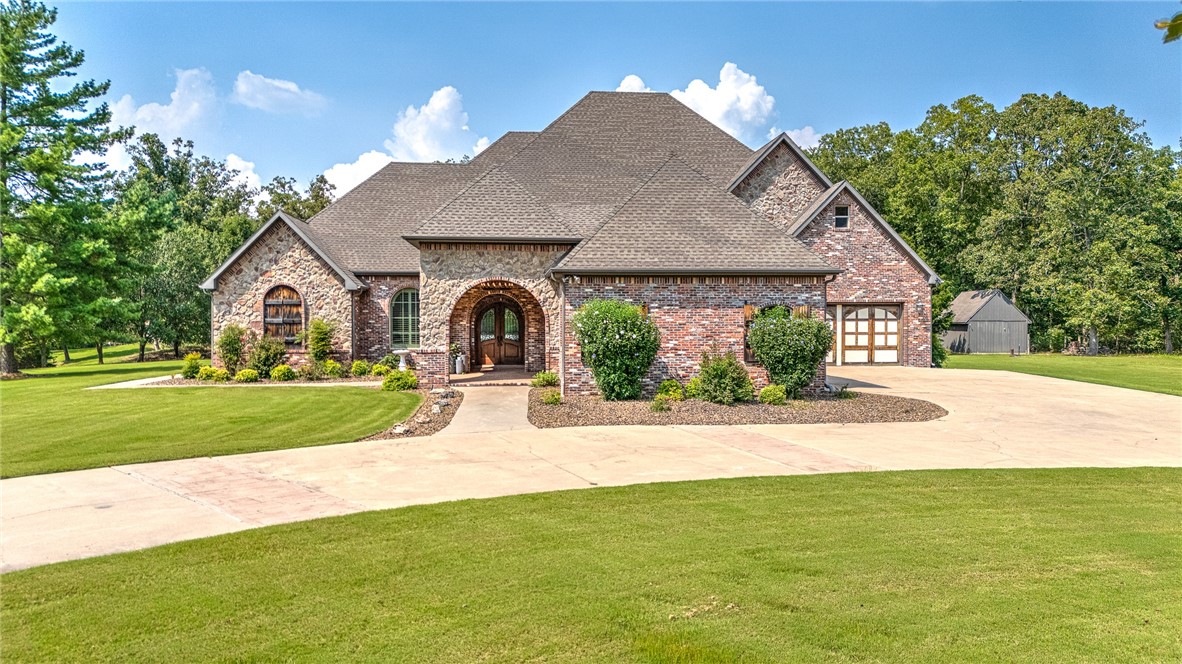 Brick-and-stone home with an arched entry, broad driveway, and landscaped lawn.