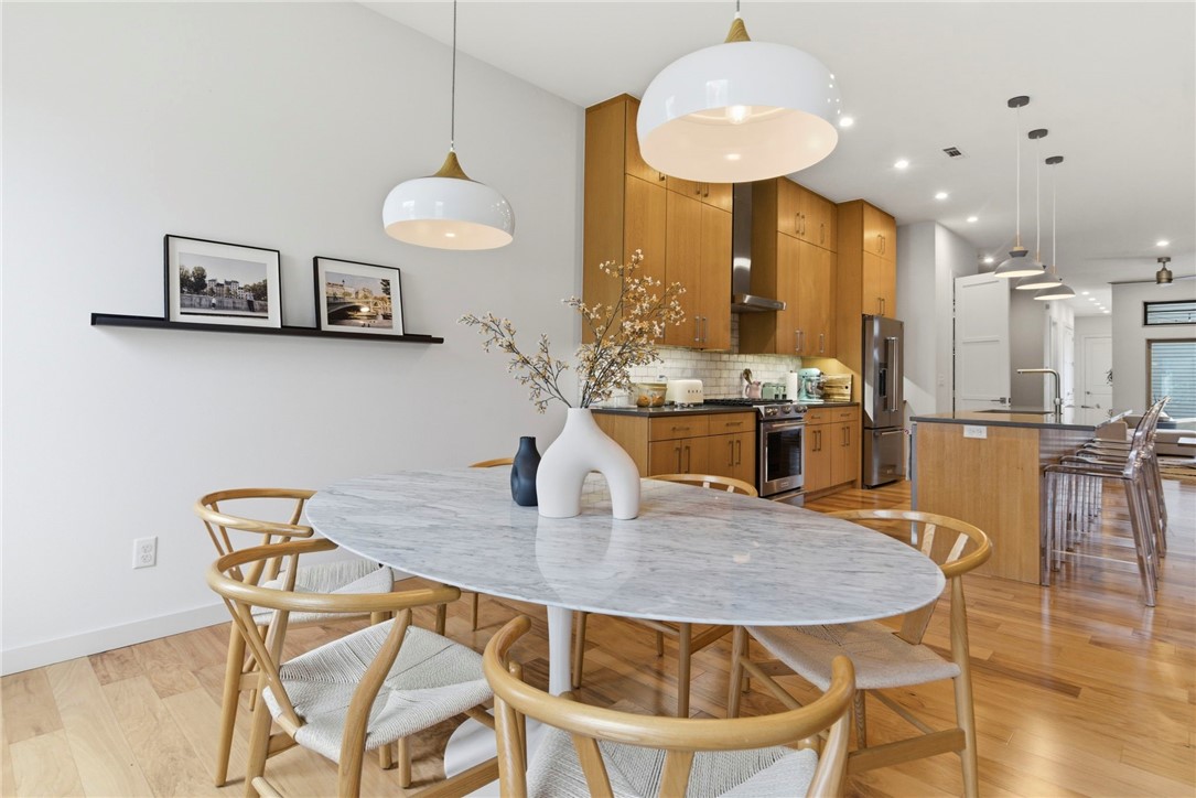Open-plan kitchen and dining area with warm wood cabinets and a large marble table.