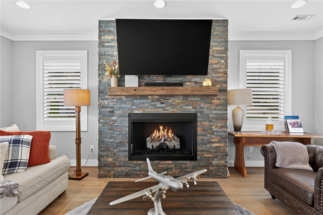 Staged living room with a stone fireplace, mounted television, and airplane sculpture on the coffee table.
