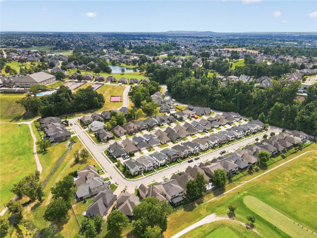 Aerial view of a residential neighborhood with tree-lined streets, green space, and a pond.