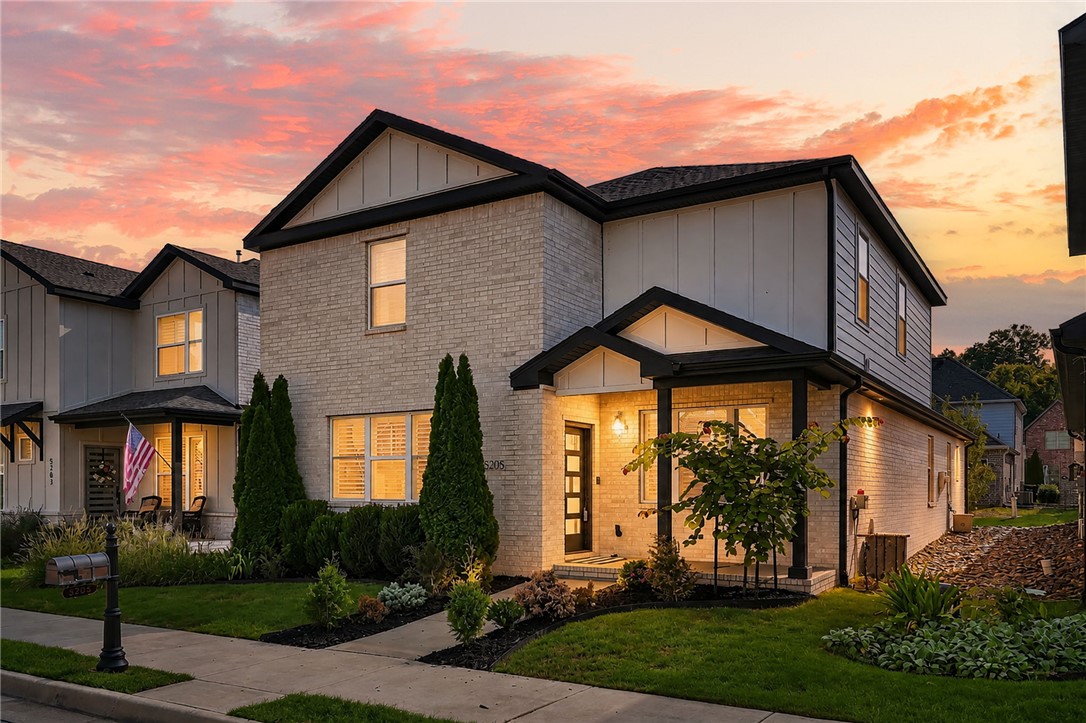 Two-story brick house at dusk with a covered entry and landscaped front yard.