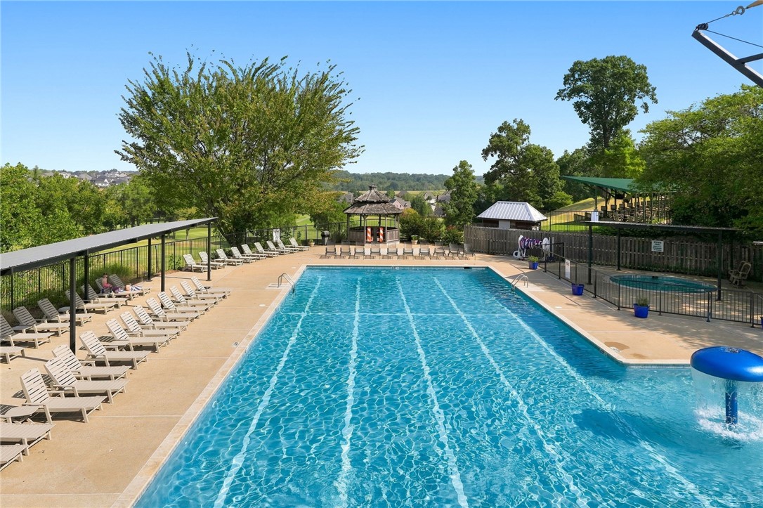 Outdoor swimming pool with lap lanes, lounge chairs, and a pavilion.