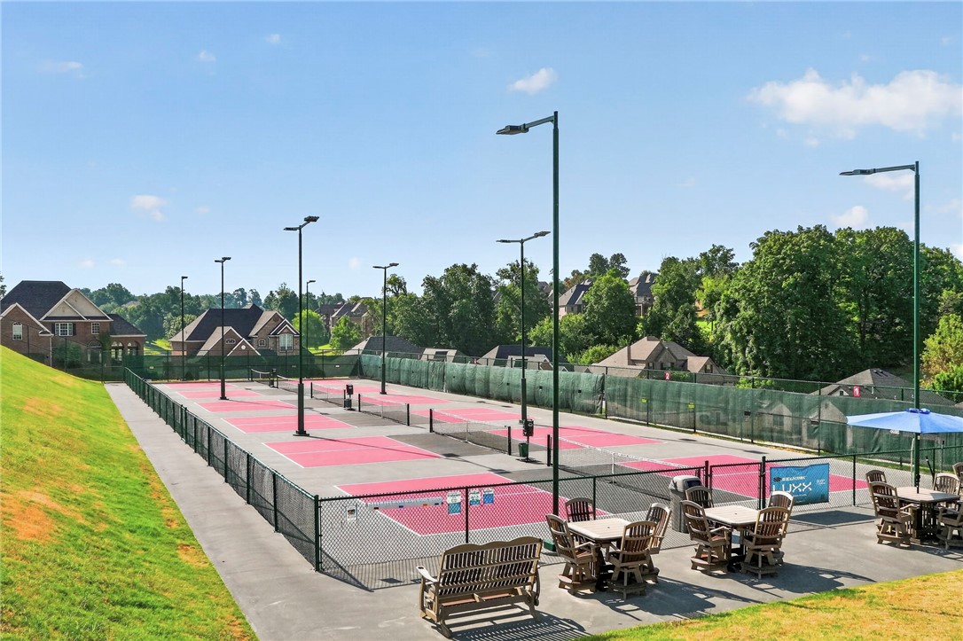 Community pickleball courts with pink surfaces, surrounded by homes and trees.