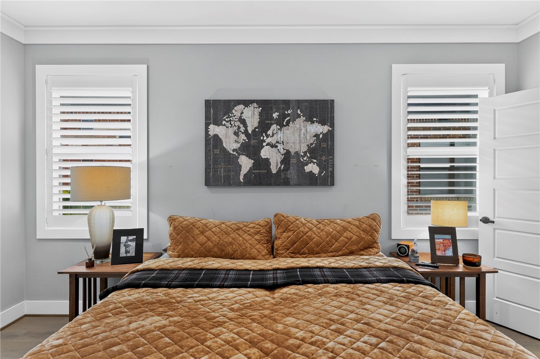 Bedroom with a tan quilted bed, plantation shutters, and a world map above the headboard.