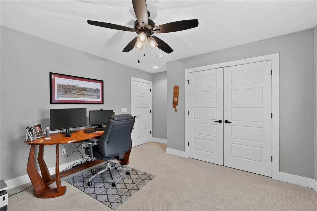 Furnished home office with a wooden desk, dual monitors, and white double closet doors.