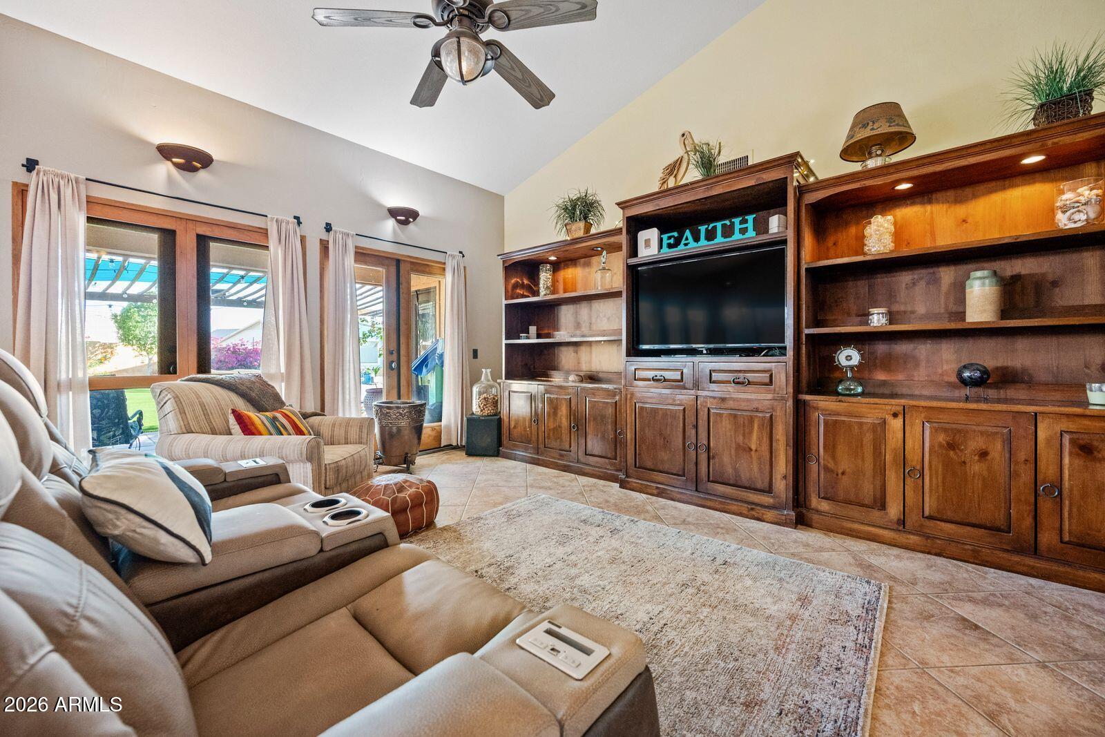 Living room with vaulted ceiling, beige sectional, and large built-in wooden entertainment center.