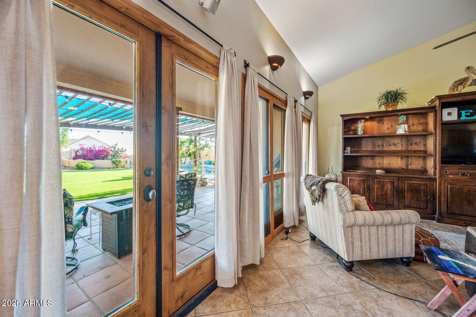 Living room with wood-framed patio doors overlooking a lawn and pool.