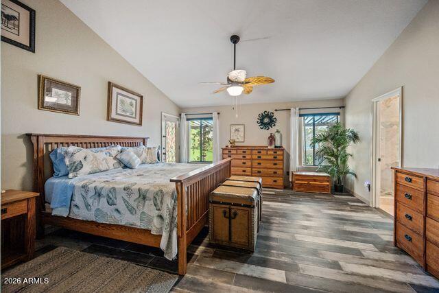 Furnished bedroom with a wooden four-poster bed, matching dressers, and windows overlooking greenery.