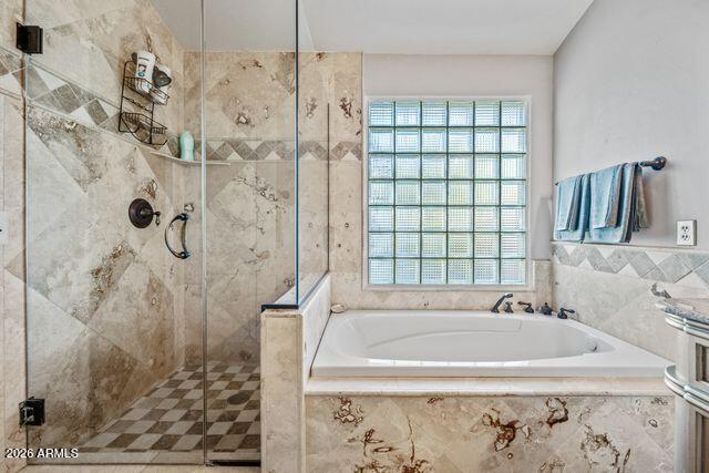 Bathroom with a jetted tub beneath a glass-block window and an adjacent glass-enclosed shower.