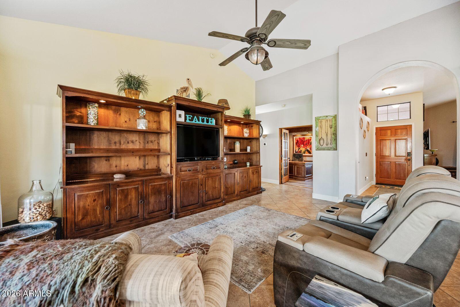 Living room with a large wooden entertainment center, leather sectional, and arched entryway.