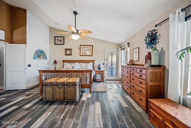 Furnished bedroom with a wooden bed, large dresser, ceiling fan, and multicolored plank flooring.