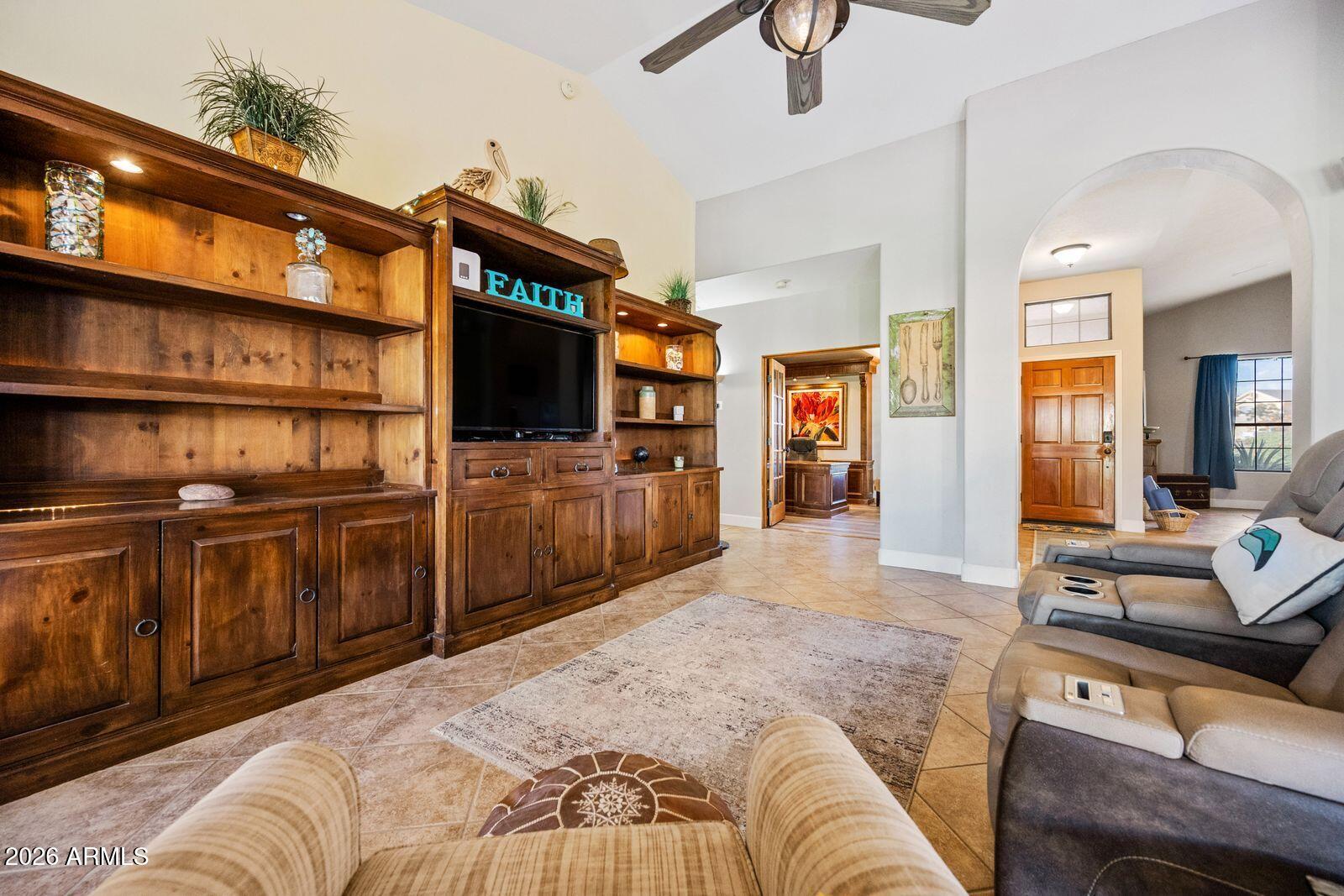Furnished living room with a dark wood built-in entertainment center and arched opening to the entry.