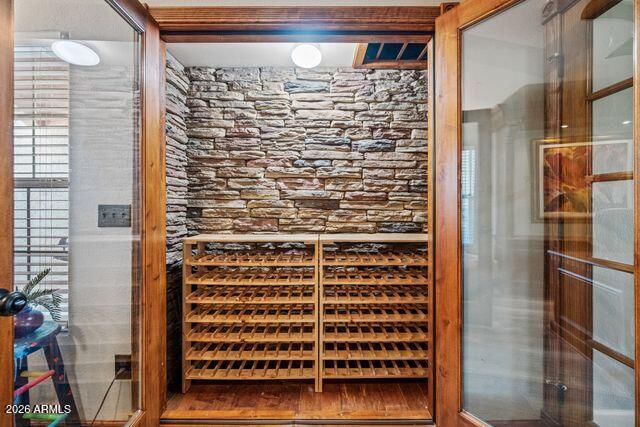 Wine cellar with stone walls, wooden wine racks, and glass doors.
