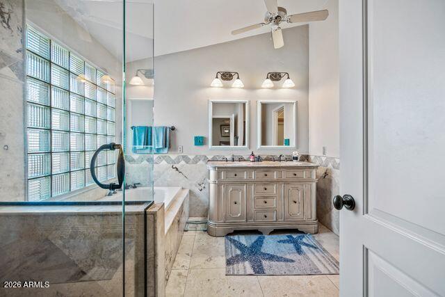 Bathroom with glass-enclosed tub, ornate double vanity, and large window with blinds.