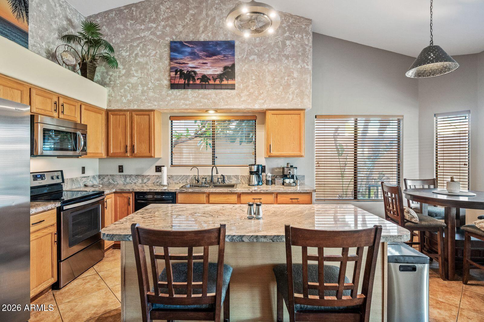 Kitchen with wood cabinets, granite island, stainless steel appliances, and an adjoining dining area.