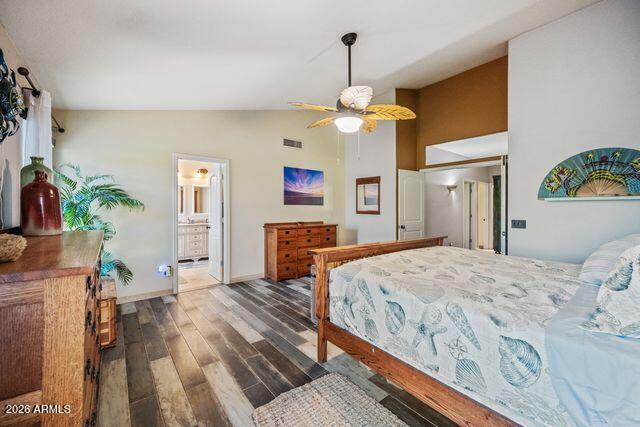 Bedroom with seashell-patterned bedding, a wooden bed and dresser, and a ceiling fan.