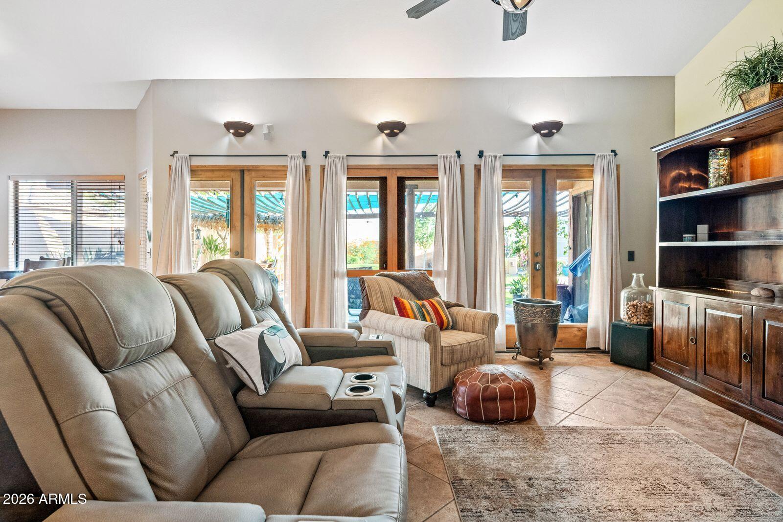Living room with a gray leather sectional and French doors opening to a covered patio.