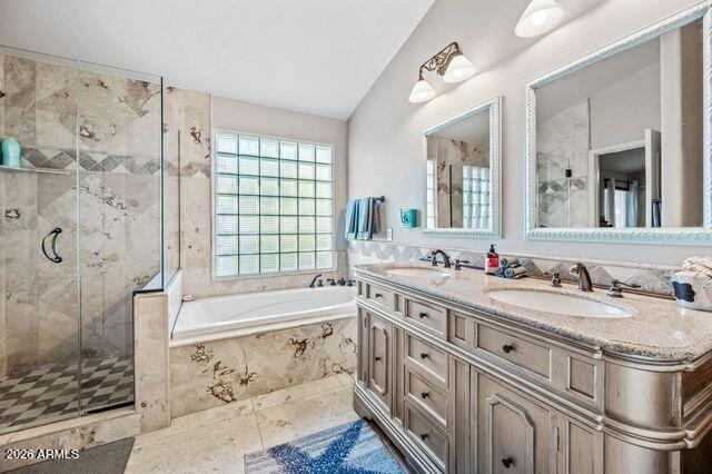 Bathroom with a corner soaking tub, glass shower, and long double vanity beneath two mirrors.