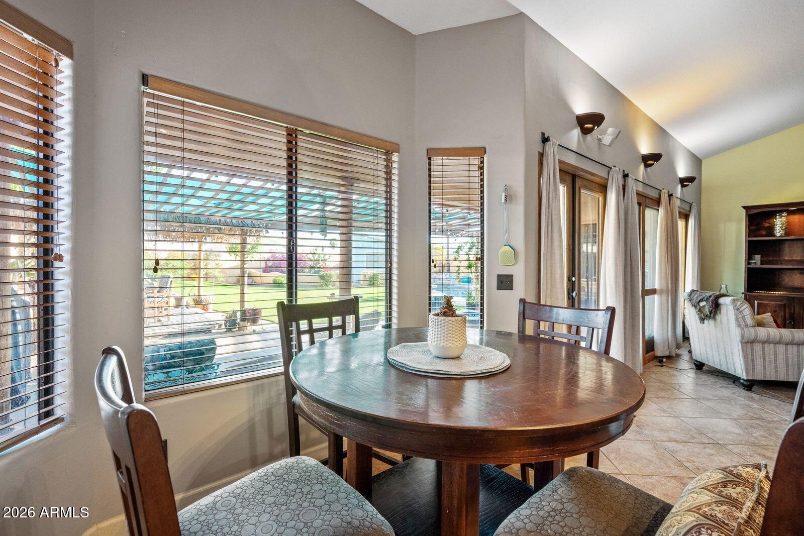 Dining area with a round wooden table, large windows, and a view of the covered patio.