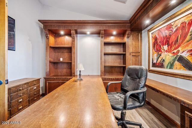 Home office with built-in wooden shelving, a large desk, and colorful floral artwork.