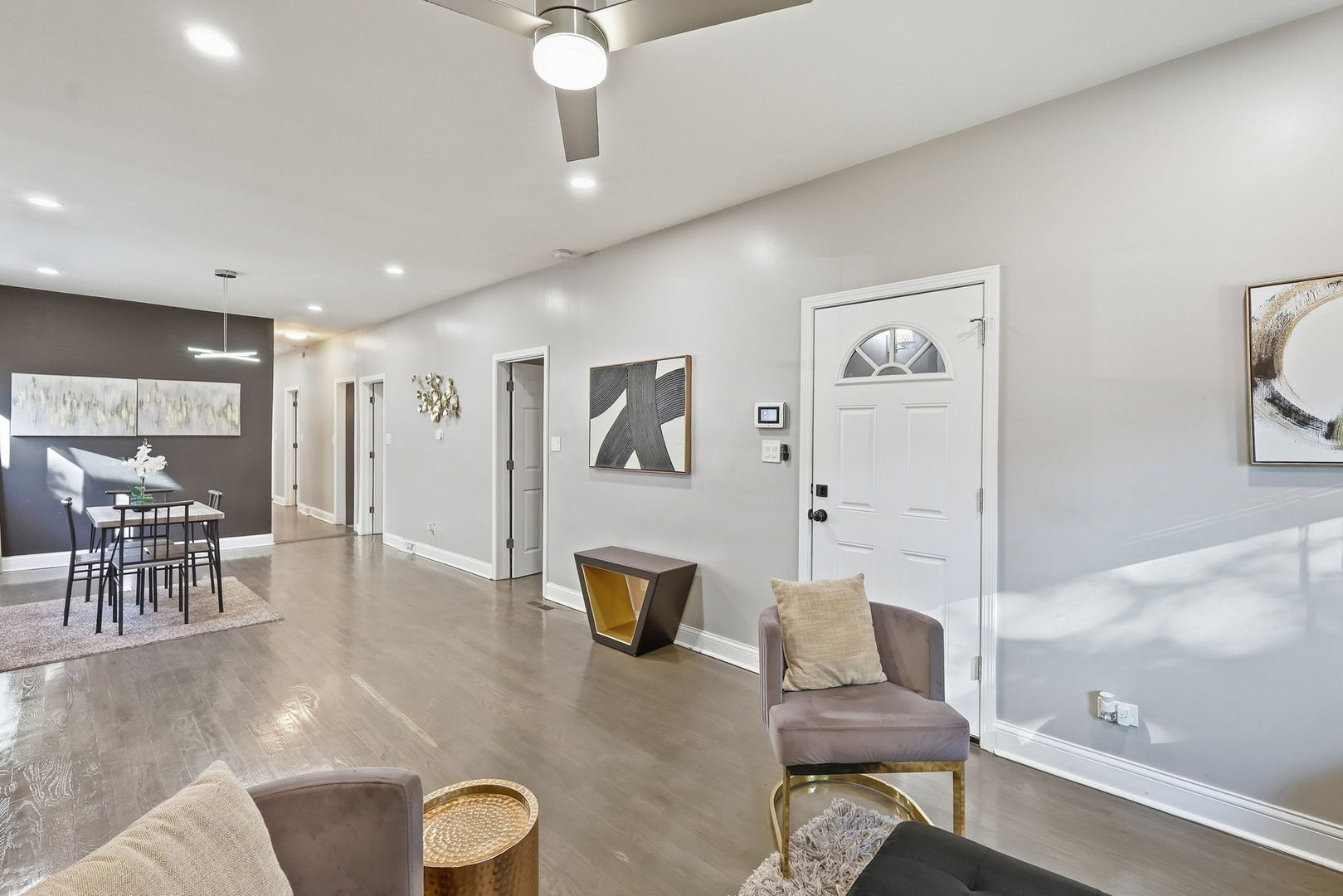 Open living and dining area with gray flooring, contemporary furnishings, and a white entry door.